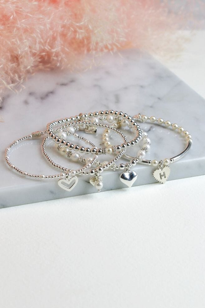 A sophisticated personalised stack featuring five new Annie Haak charm bracelets with a choice of initial.
