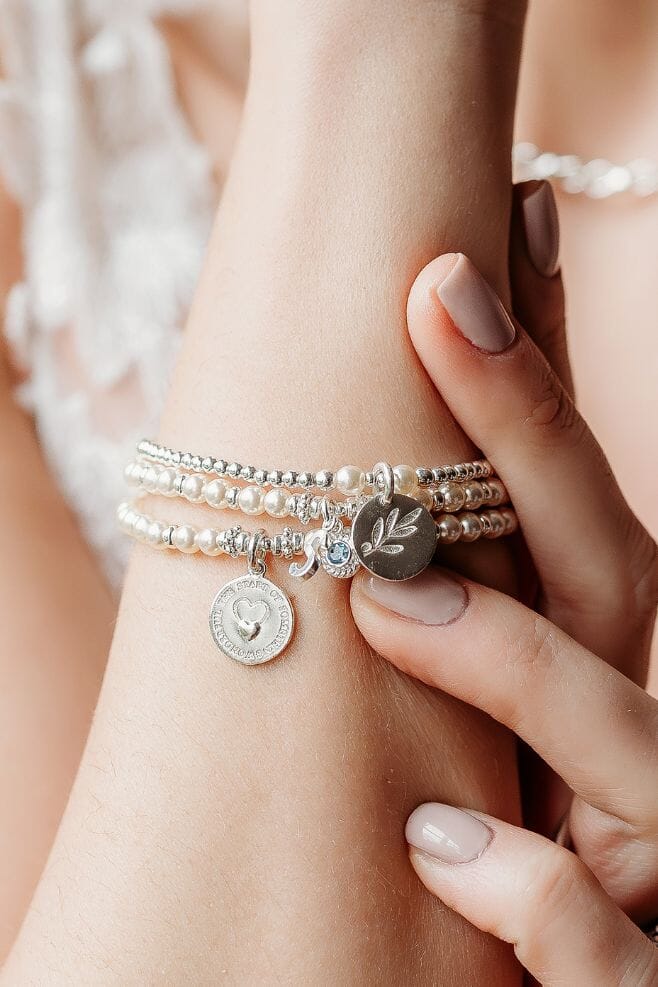 A delicate 925 Sterling Silver bracelet featuring Preciosa Pearls, a Blue Topaz pendant and your choice of initial charm.