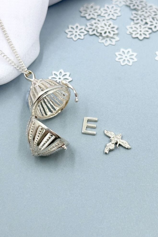An oval shaped 925 Sterling Silver locket necklace, featuring an Initial and Angel charm.