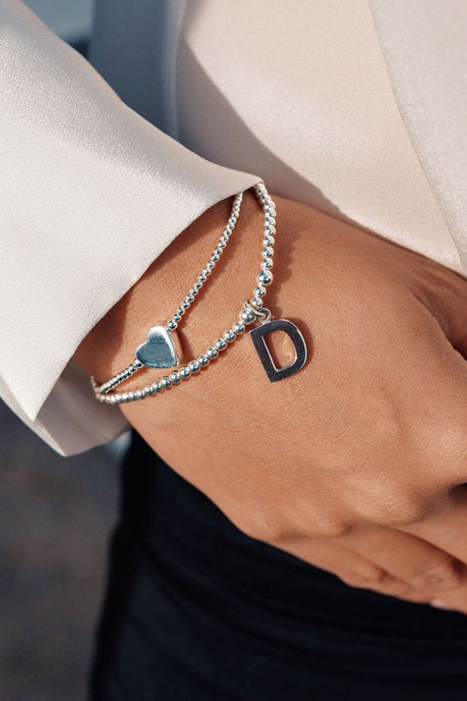 A double strand bracelet is hand-threaded with 925 Sterling Silver beads and your choice of initial.