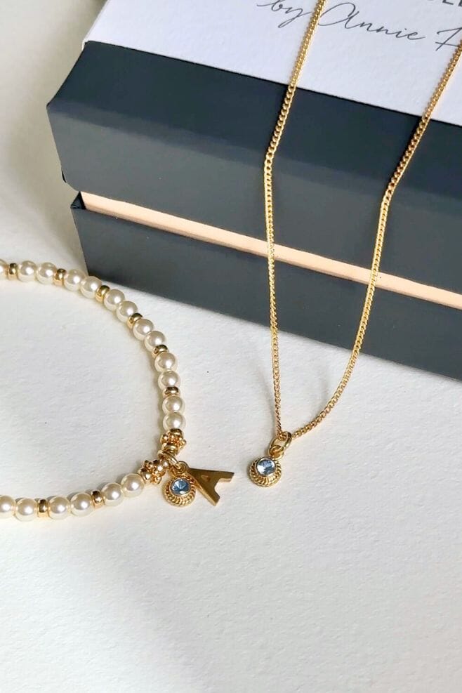 A delicate gold plated Silver bracelet and necklace featuring Preciosa Pearls, a Blue Topaz pendant and your choice of initial charm.