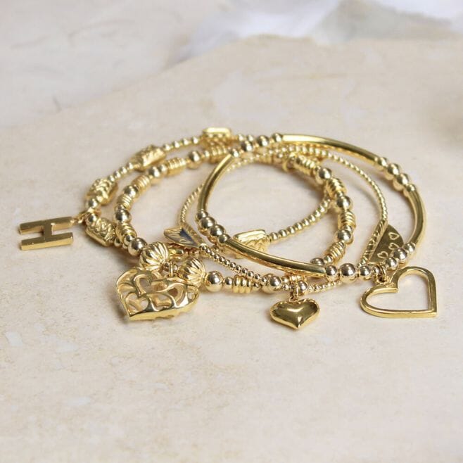 A personalised four-strand bracelet stack, featuring 18 ct gold plated 925 Sterling Silver and heart charms.