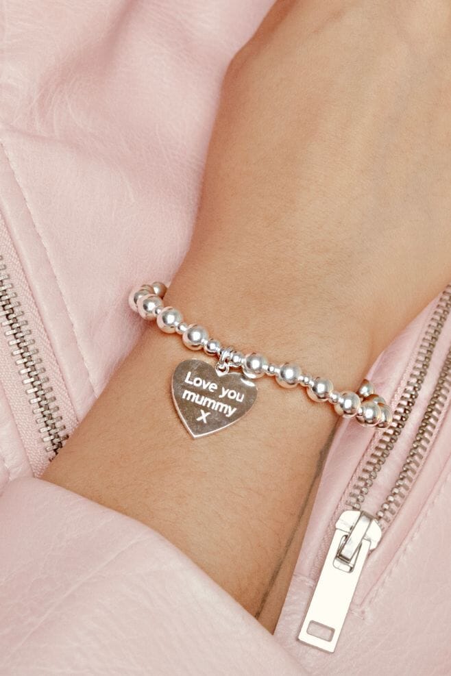 Our Orchid single strand bracelet is hand-threaded with 925 Sterling Silver beads. Personalise the heart charm with an engraving!
