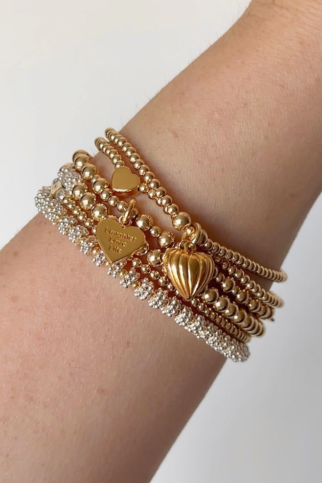 A three-strand bracelet stack, featuring sweet heart charms.