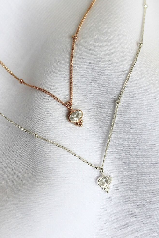 An intricate pendant with Zirconia crystal and a three-dot cluster detail, hanging from a unique dainty chain.