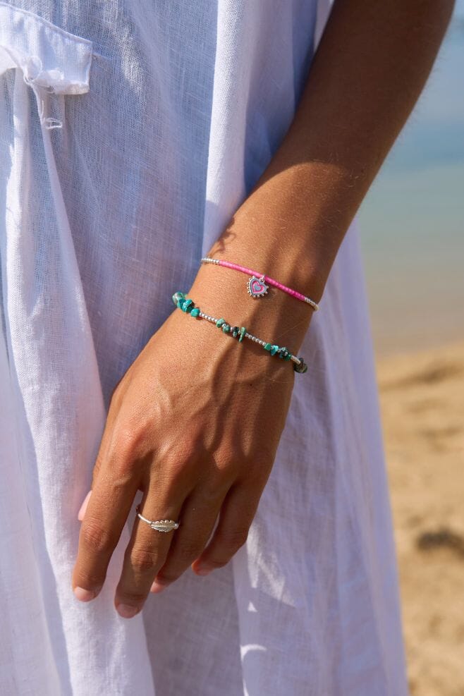 A pink friendship bracelet crafted with gold-plated silver, glass beads, and high quality cord.