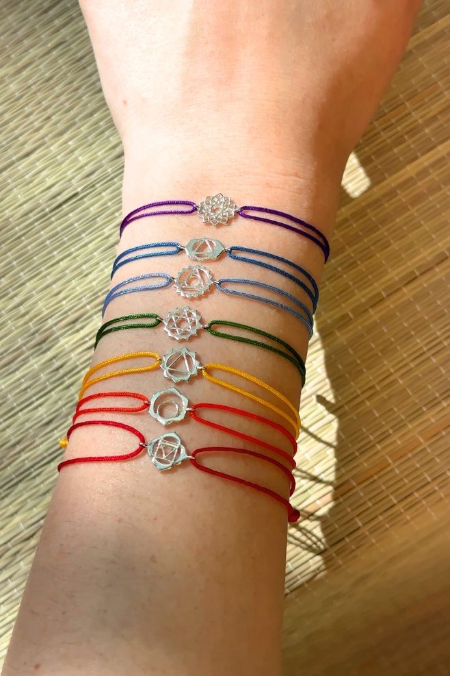 A colourful rainbow of woven friendship bracelets featuring Chakra symbols.