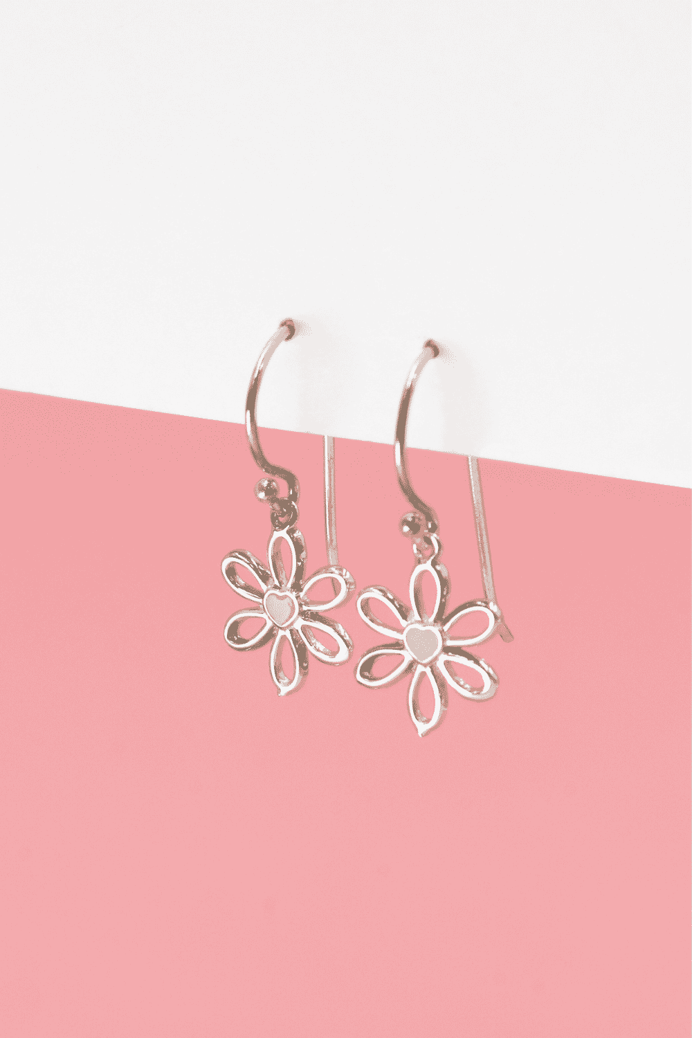Bring a soft touch of floral charm to your look with the Pink Daisy Silver Hook Earrings. These dainty earrings feature beautifully crafted daisy charms, each adorned with a tiny heart at the centre filled with premium Italian enamel in a gentle pink hue.