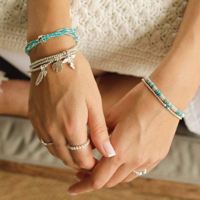 A three-strand bracelet stack featuring the Tree of Life, My Guardian Angel and Feather charms.